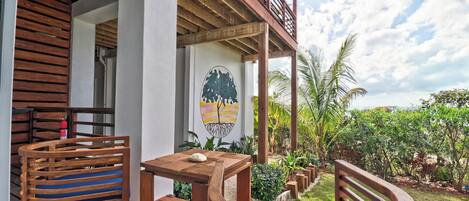 Una terraza de madera con sillas y una mesa, un extintor y un mural de un árbol.