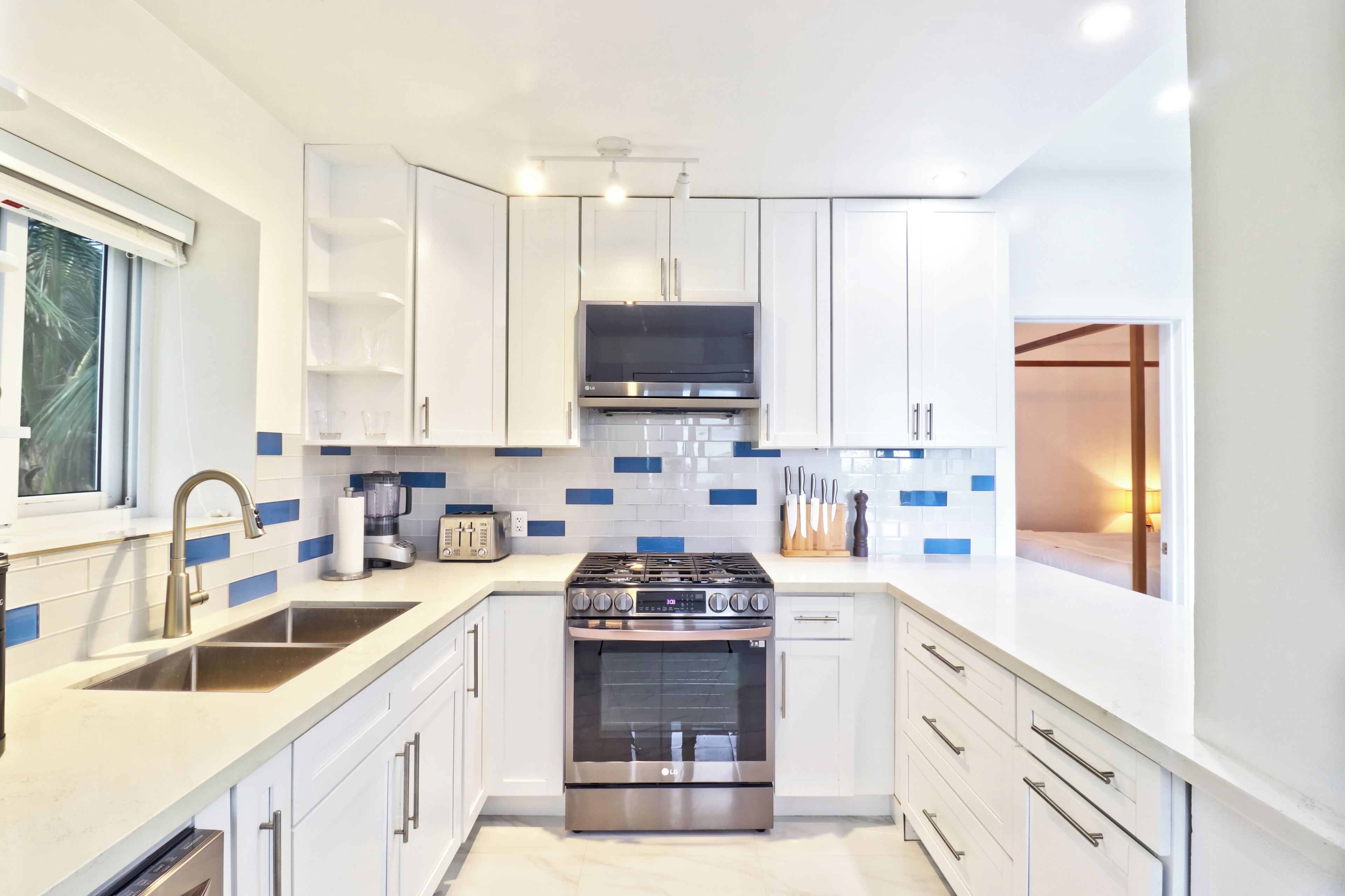 A modern kitchen with white cabinets, a stainless steel stove, and a window with a view.