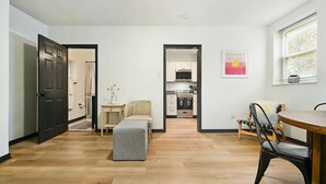 Un apartamento moderno con comedor, kitchenette y sala de estar con sofá y reposapiés.