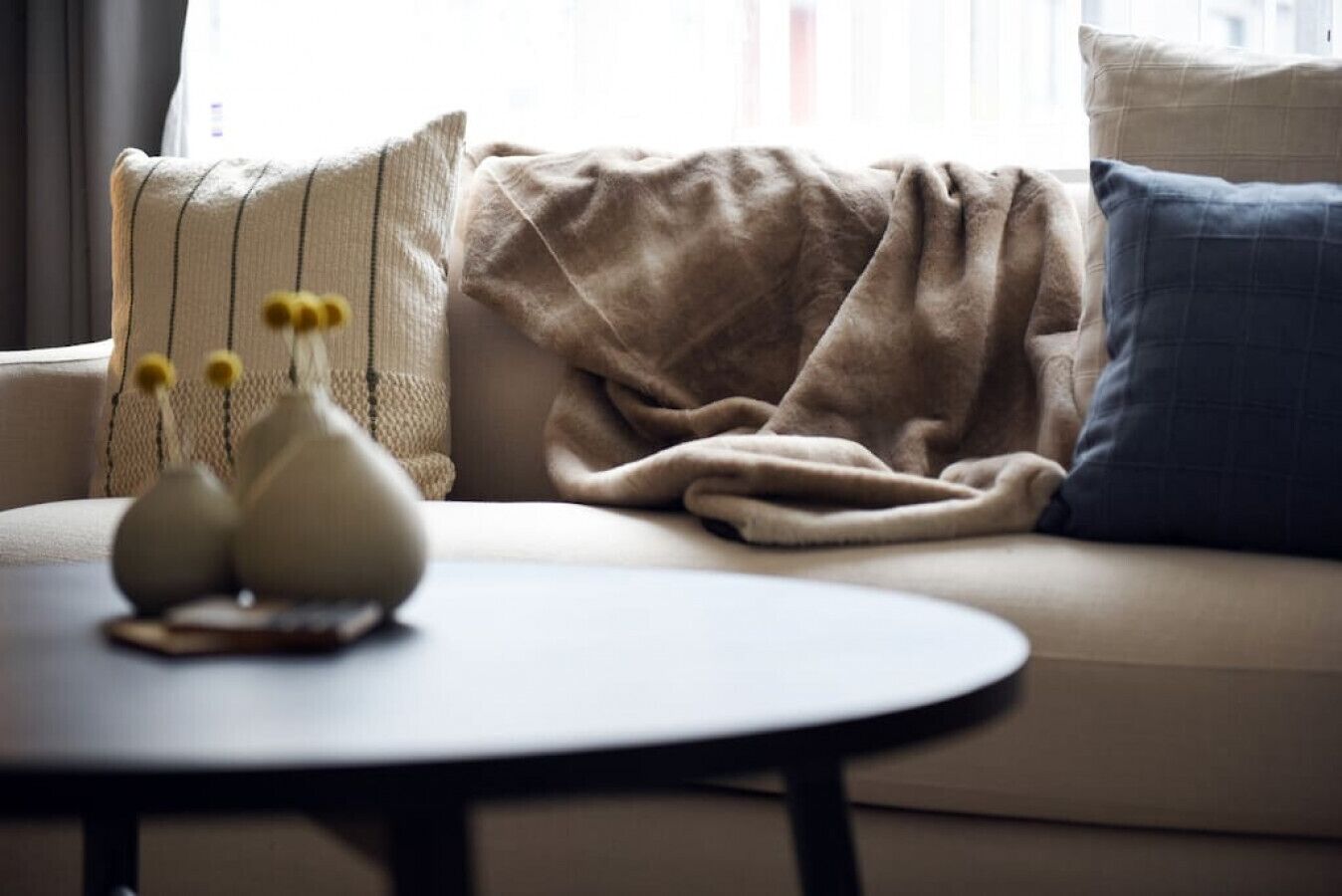 A living room with a sofa, a round table, and decorative vases.