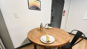 A round wooden table with two plates, one with a rolled napkin and a cocktail shaker, and another with a folded napkin. A black chair is positioned at the table. - ★ HostWise Stays ★ Pet Friendly, Butler St. Apt with Private Entrance (Pittsburgh)