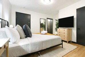 A modern bedroom with a bed, bedside tables, a dresser, a TV, and a mirror. - ★ HostWise Stays ★ Pet Friendly, Butler St. Apt with Private Entrance (Pittsburgh)