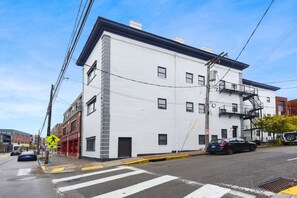 A white building with a fire escape on the side, a pedestrian crossing, and a street with cars. - Butler St Cozy Retreat, Walk to Breweries & Shops (Pittsburgh)