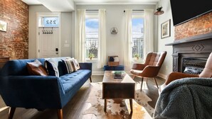 A living room with a blue sofa, a brown leather chair, a coffee table, and a fireplace. - ★ HostWise Stays ★ Family Friendly, Great Area, Artist Abode! (Pittsburgh)