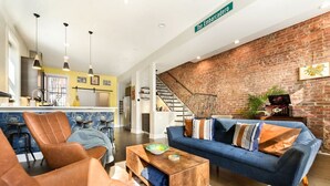 A modern living room with a blue sofa, leather armchairs, and a wooden coffee table. - ★ HostWise Stays ★ Family Friendly, Great Area, Artist Abode! (Pittsburgh)
