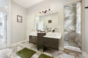 Une salle de bain moderne avec deux lavabos, un grand miroir et un espace douche aux carreaux de marbre.