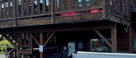 A wooden building with a balcony and a hot tub in front.