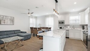 A modern kitchen with white cabinets, a central island, and stainless steel appliances. - New Constructed Luxury 3-BD House in Mid-City (New Orleans)