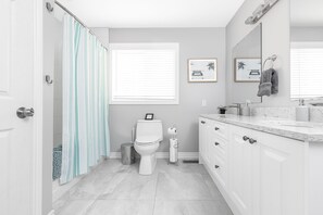 A modern bathroom with a toilet, shower curtain, vanity, and a large mirror. - Modern cottage escape in Muskoka (Huntsville)