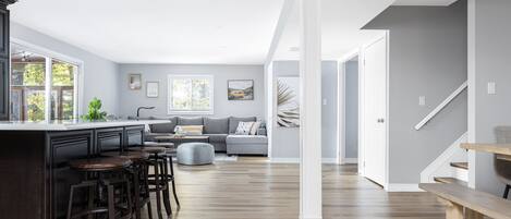 A modern kitchen with a central island, bar stools, and a dining area with a bench.