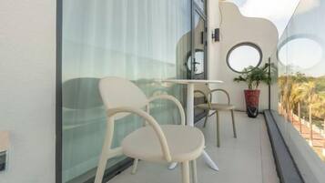 A balcony with two chairs, a small table, and a potted plant.