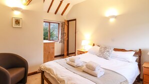 Une chambre à coucher avec un lit en bois, une table de chevet avec une lampe, une chaise et une fenêtre avec des rideaux.