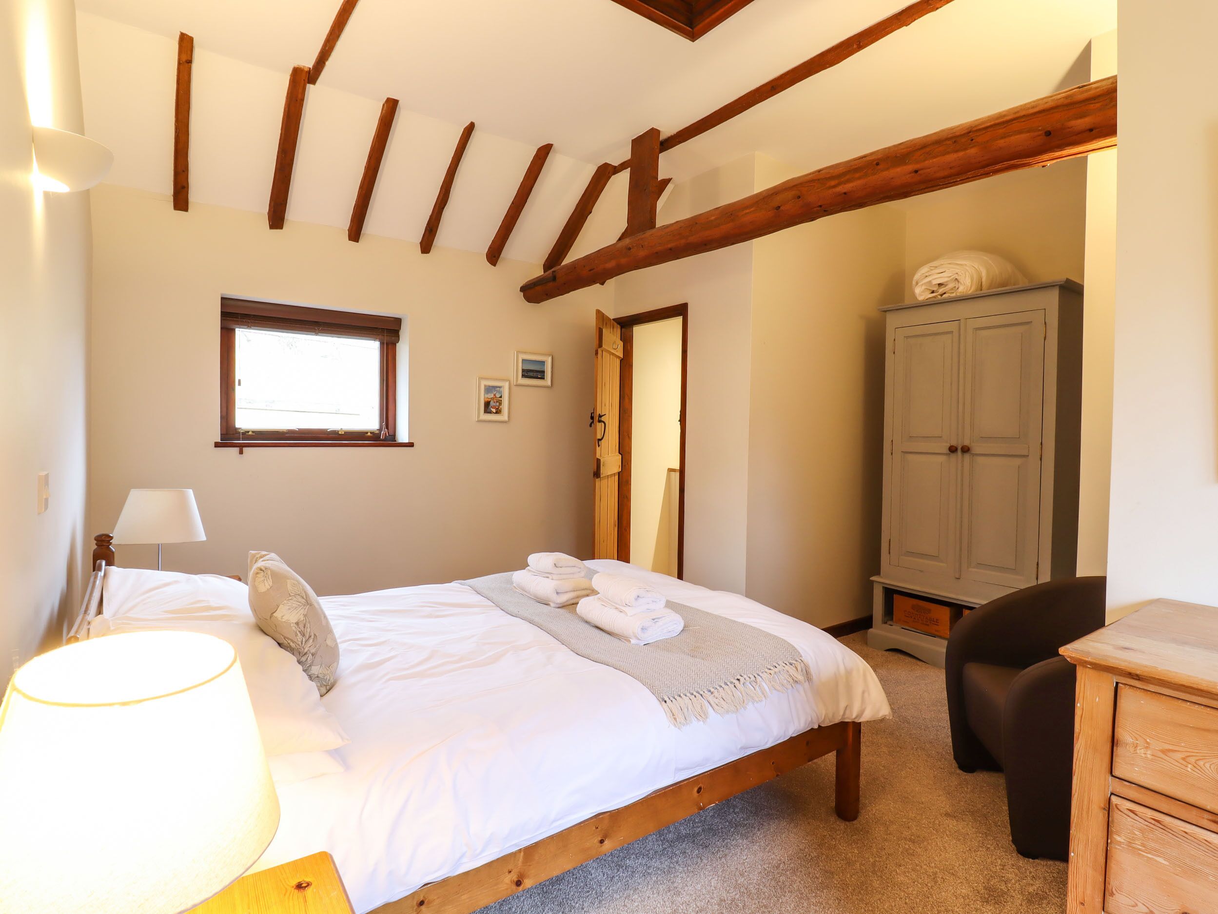 A bedroom with a bed, a lamp, a wardrobe, and a window.