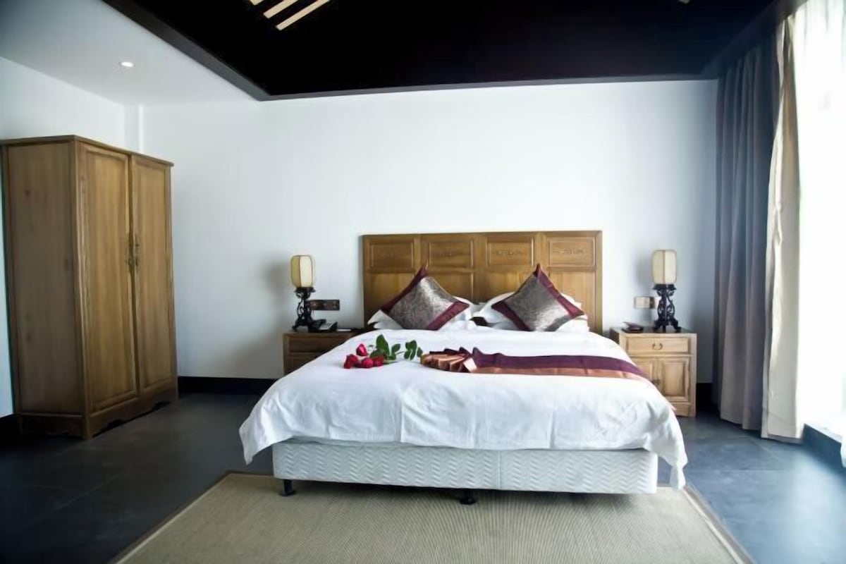 Un dormitorio ordenado con una cama grande, cabecera de madera, mesitas de noche y un armario.