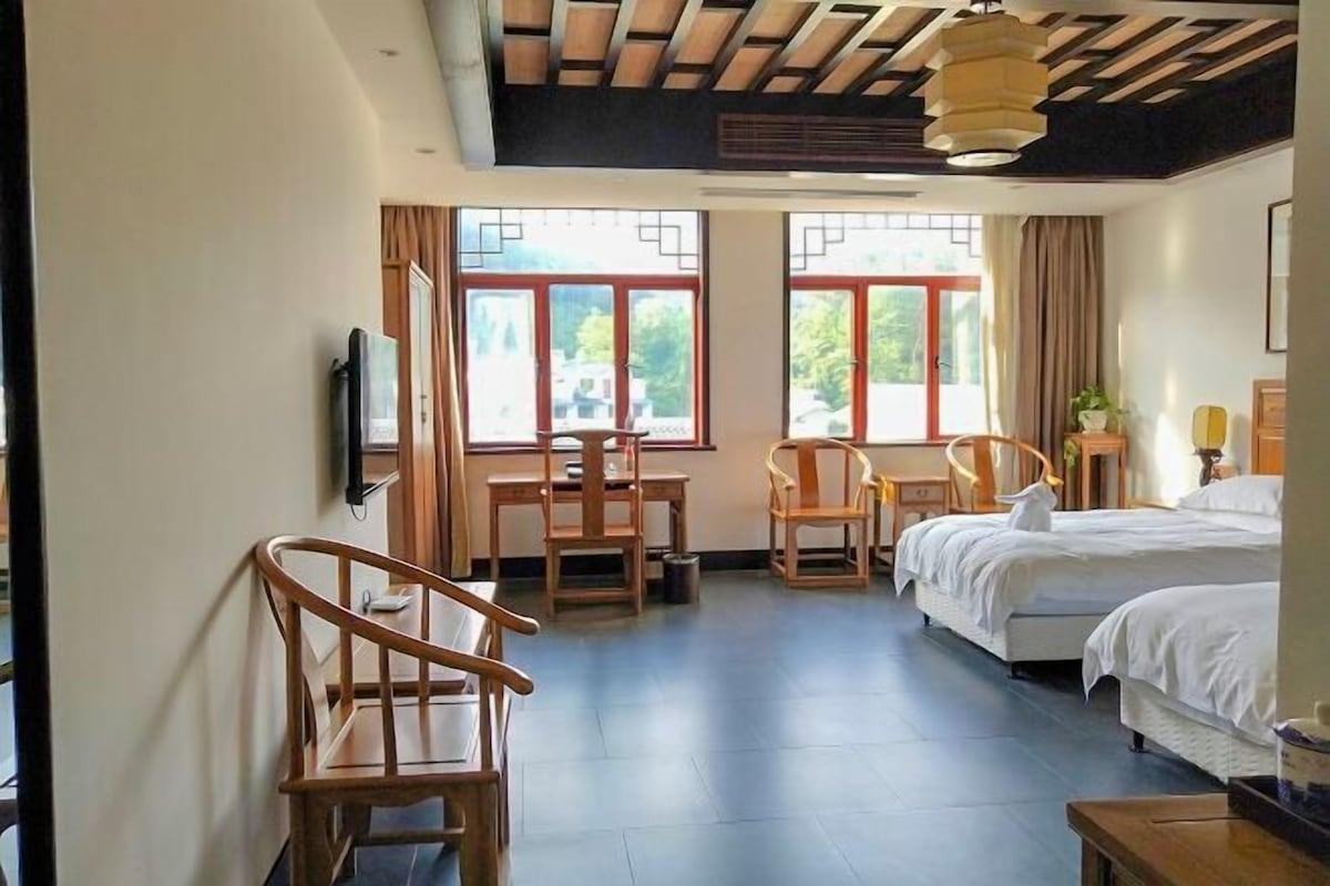 Una habitación de hotel con cama, dos sillones, un escritorio y una televisión.