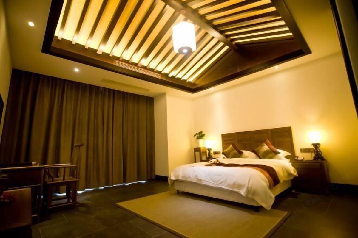 Ein Hotelzimmer mit einem großen Bett, einem Schreibtisch und einer Deckenleuchte.