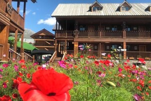 Un edificio de madera con balcones y un jardín de flores al frente.