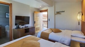 Habitació d'hotel amb dos llits, un televisor, un taulell de fusta i un balcó.