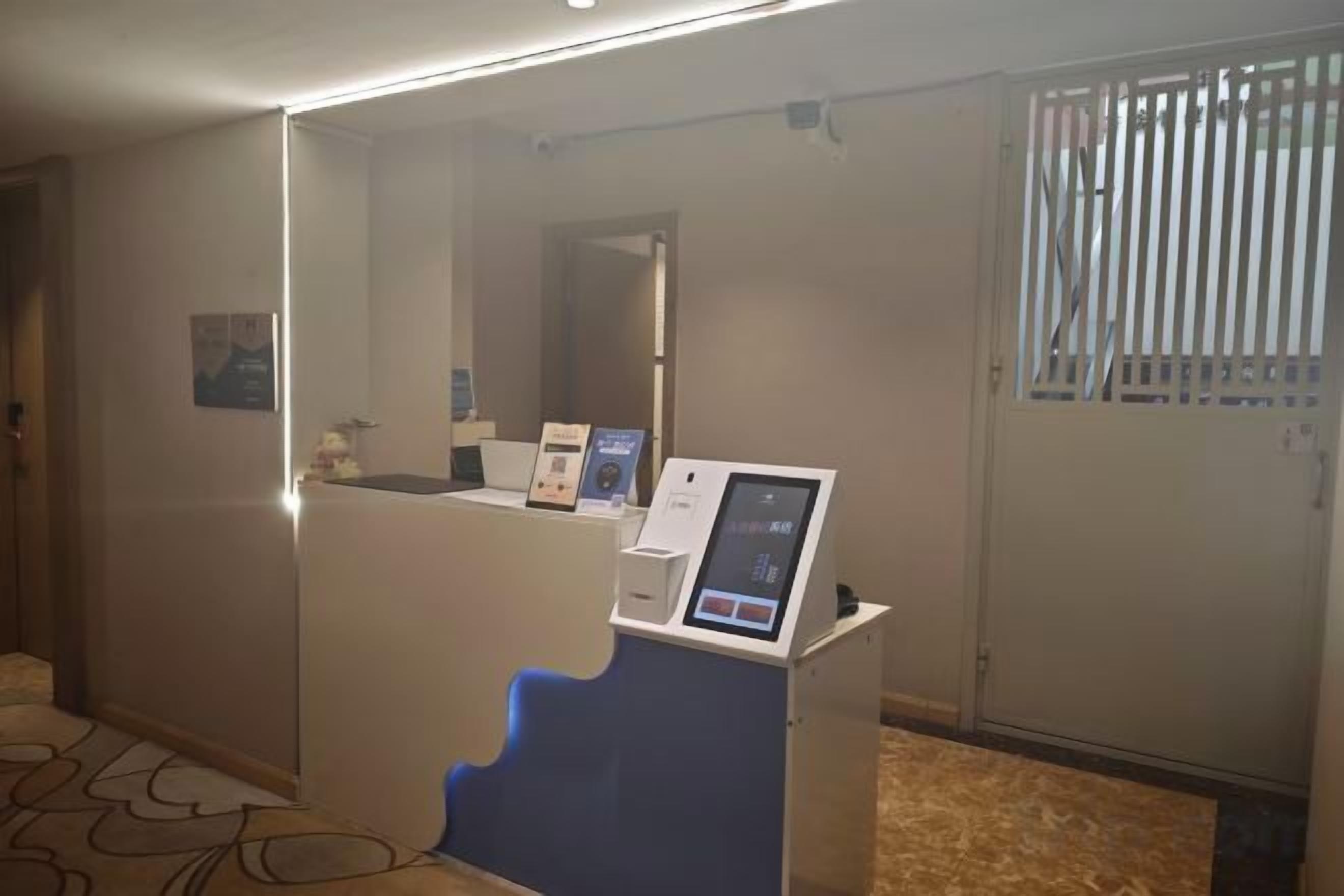 A reception area with a counter, a digital kiosk, and a door with a window.