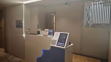A reception area with a counter, a digital kiosk, and a door with a window.