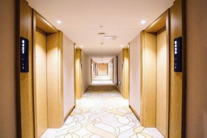 A hotel corridor with wooden doors and a patterned carpet. - HAI FU JING (Guiyang)