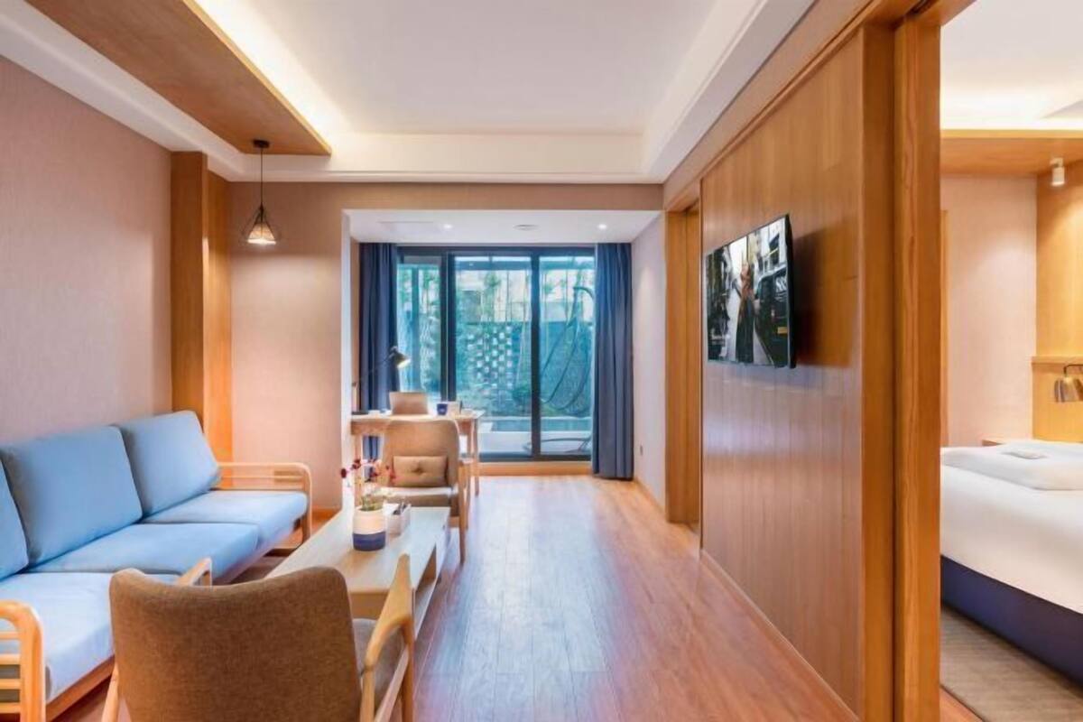 A hotel room with a sofa, a dining table, a TV, and a bed.