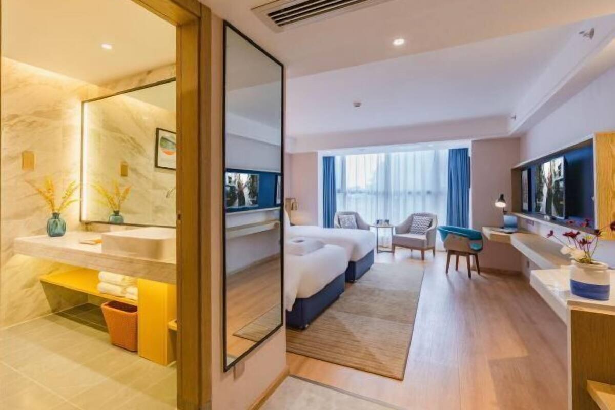 A hotel room with a bathroom, a bed, a desk, and a TV.