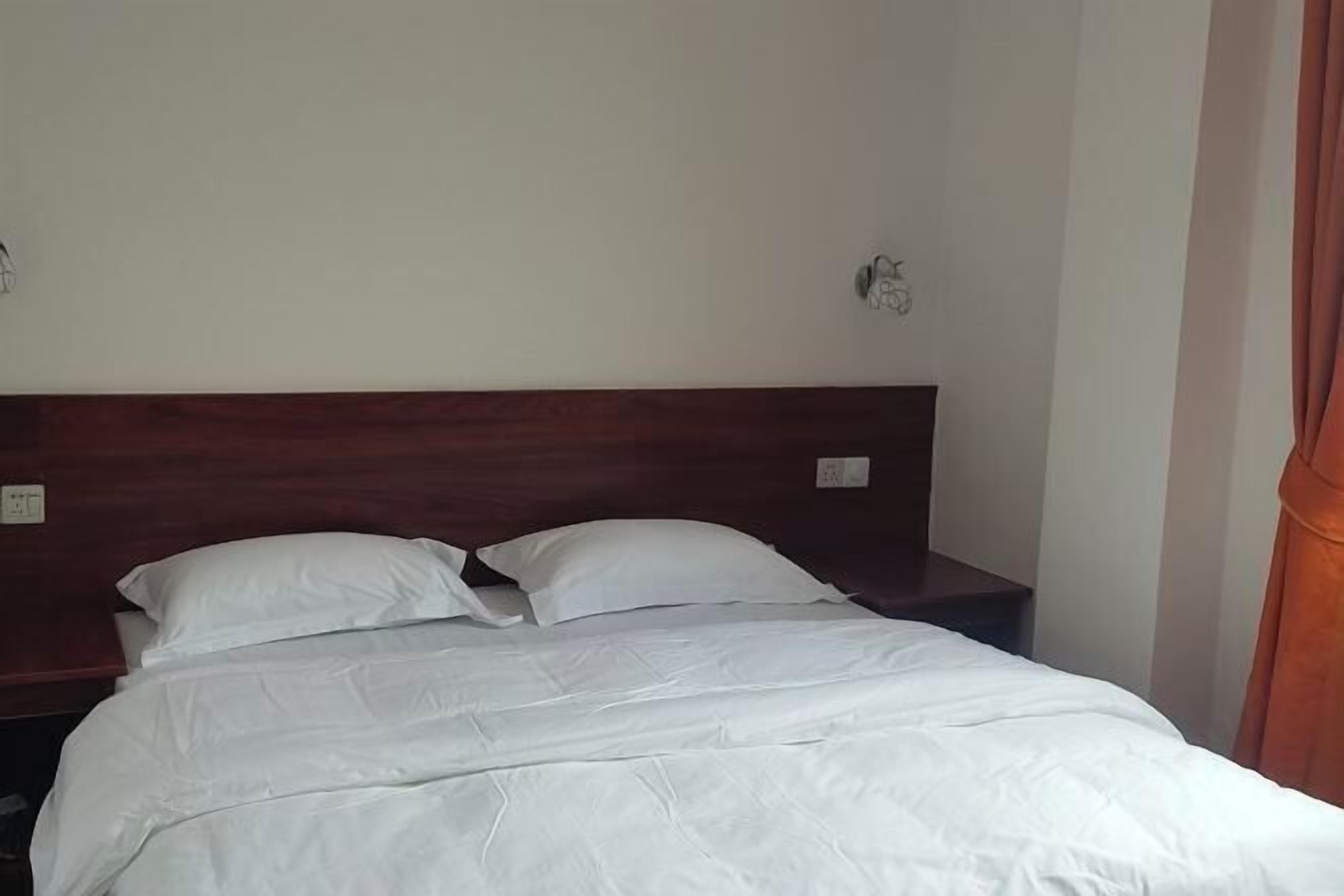 A single bed with white bedding in a room with a wooden headboard.