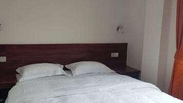 A single bed with white bedding in a room with a wooden headboard.