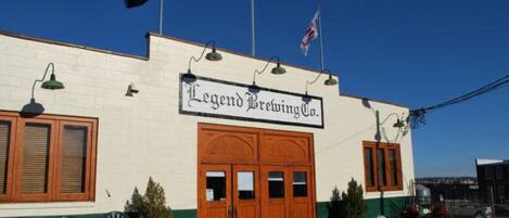 A building with a sign reading "Legend Brewing Co." and outdoor seating with tables and chairs.