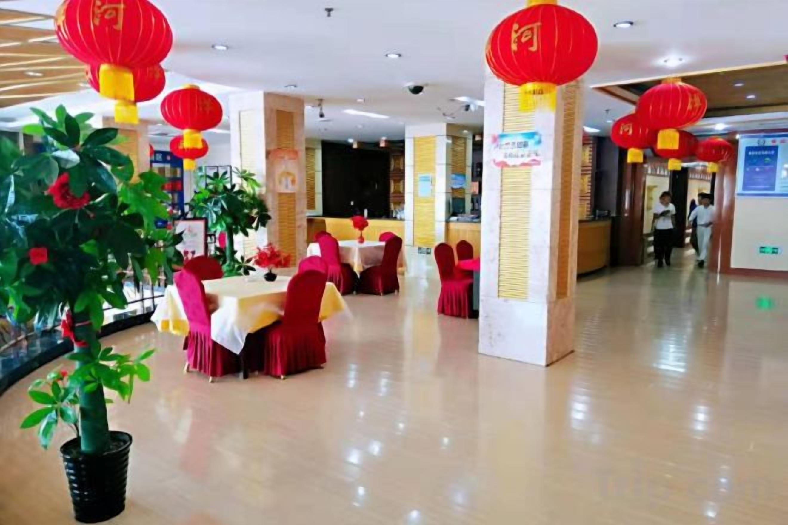 A dining area with tables and chairs, red lanterns, and a potted plant.