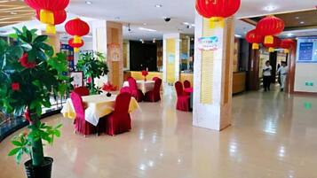 A dining area with tables and chairs, red lanterns, and a potted plant.