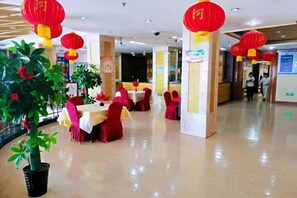 A dining area with tables and chairs, red lanterns, and a potted plant.