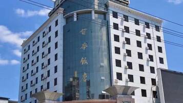 A multi-story hotel with a prominent curved glass facade and a traditional Chinese architectural design.