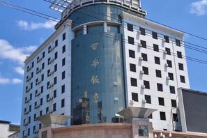 A multi-story hotel with a prominent curved glass facade and a traditional Chinese architectural design. - Gangu Hotel (Gangu)