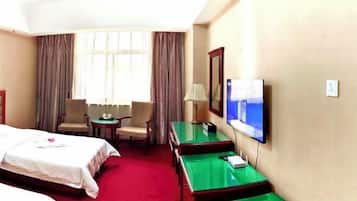 Quarto de hotel com duas camas, televisão, escrivaninha e cadeira.