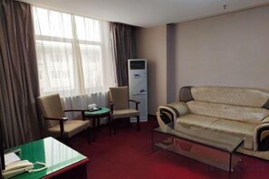 A hotel room with a sofa, two armchairs, a small table, a desk with a telephone, and a radiator. - Gangu Hotel (Gangu)