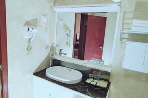 A bathroom with a white sink, a mirror above it, and a towel rack to the right. - Gangu Hotel (Gangu)
