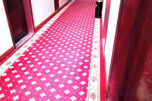 A red carpet with a white pattern leading to a door.