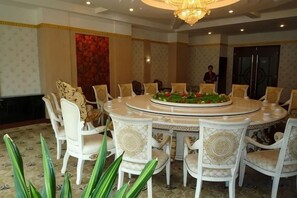 Un salón de conferencias con una mesa redonda, sillas blancas y una araña.