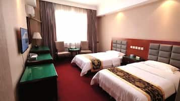 A hotel room with two beds, a desk, a chair, a TV, and a window with curtains.