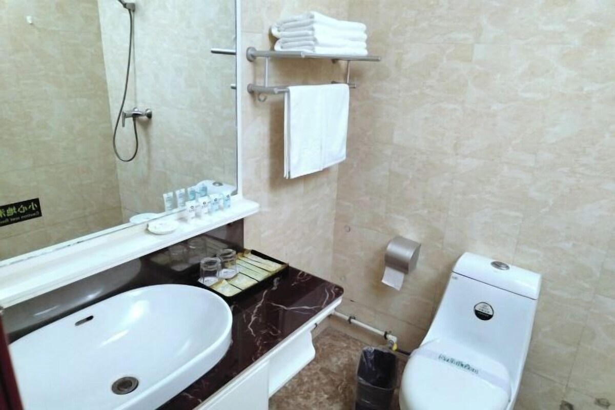 A bathroom with a white sink, a mirror, a towel rack, a toilet, and a shower.