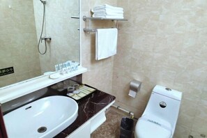 A bathroom with a white sink, a mirror, a towel rack, a toilet, and a shower. - Gangu Hotel (Gangu)