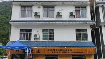 A multi-story building with a blue awning and a wooden signboard.