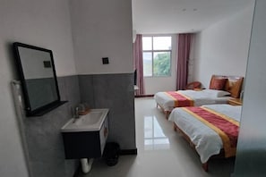 Two beds with white bedding and red accents, a sink, and a large window with curtains.