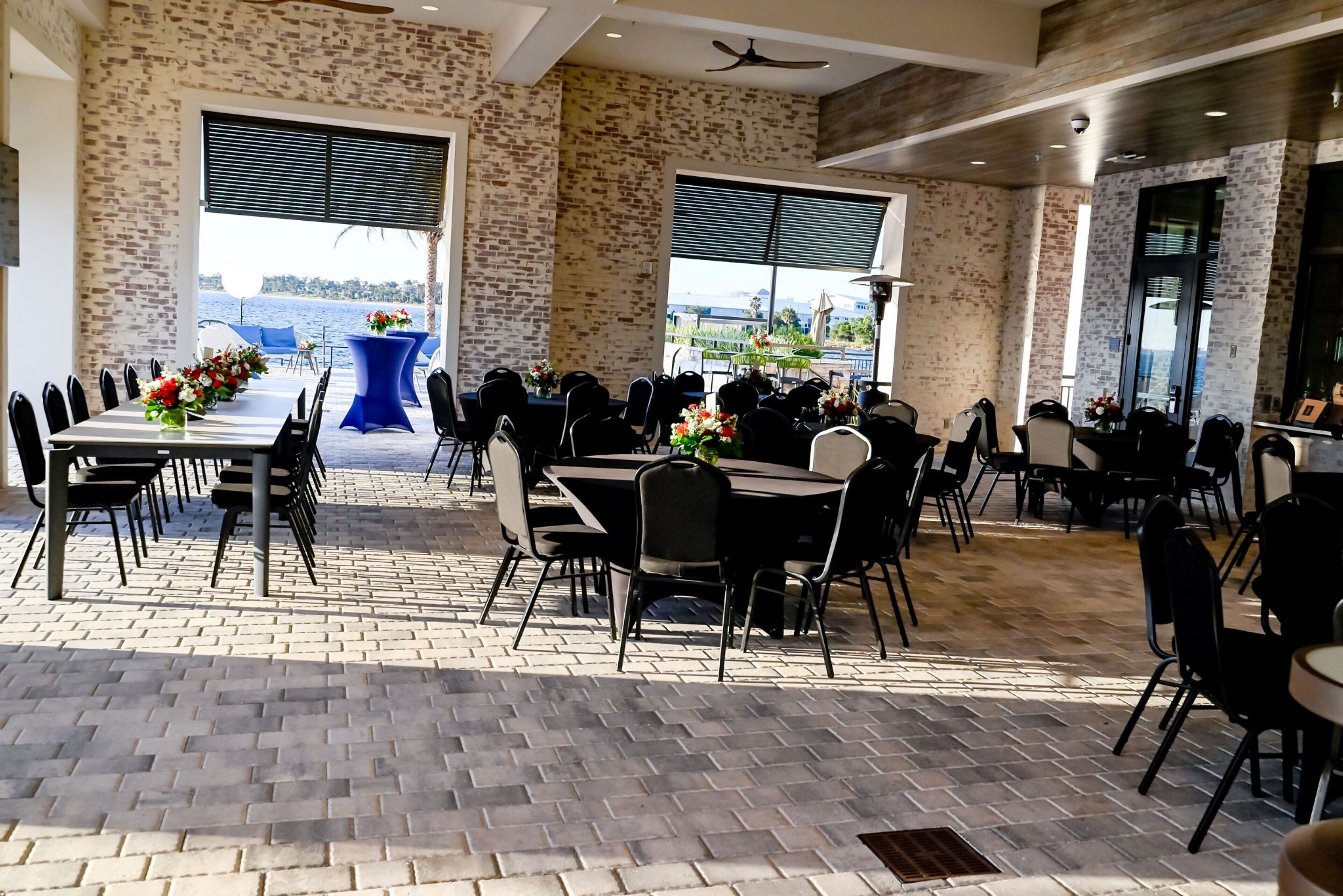 Un comedor amplio e interior con paredes de ladrillo, ventanas grandes y vistas al mar.