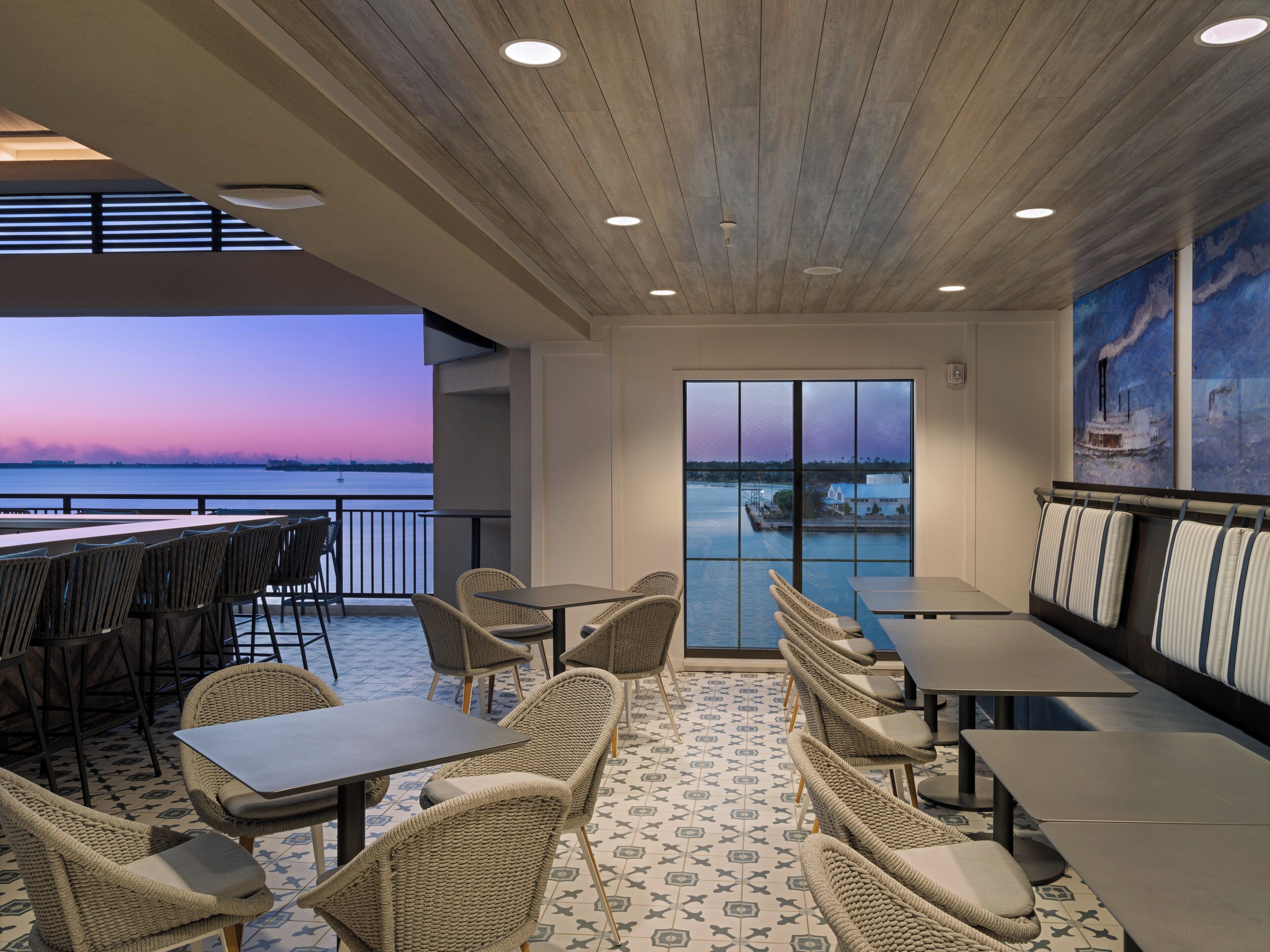 Ein Restaurant mit Außenbestuhlung, Blick auf das Wasser und Sonnenuntergang.