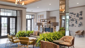 A spacious lobby with a modern chandelier, seating area with sofas and chairs, a coffee table, and a large mirror. - Hotel Indigo Panama City Marina by IHG (Panama City)