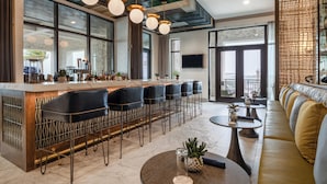 A modern bar area with a long counter, multiple bar stools, and a seating area with a sofa and a round table. - Hotel Indigo Panama City Marina by IHG (Panama City)