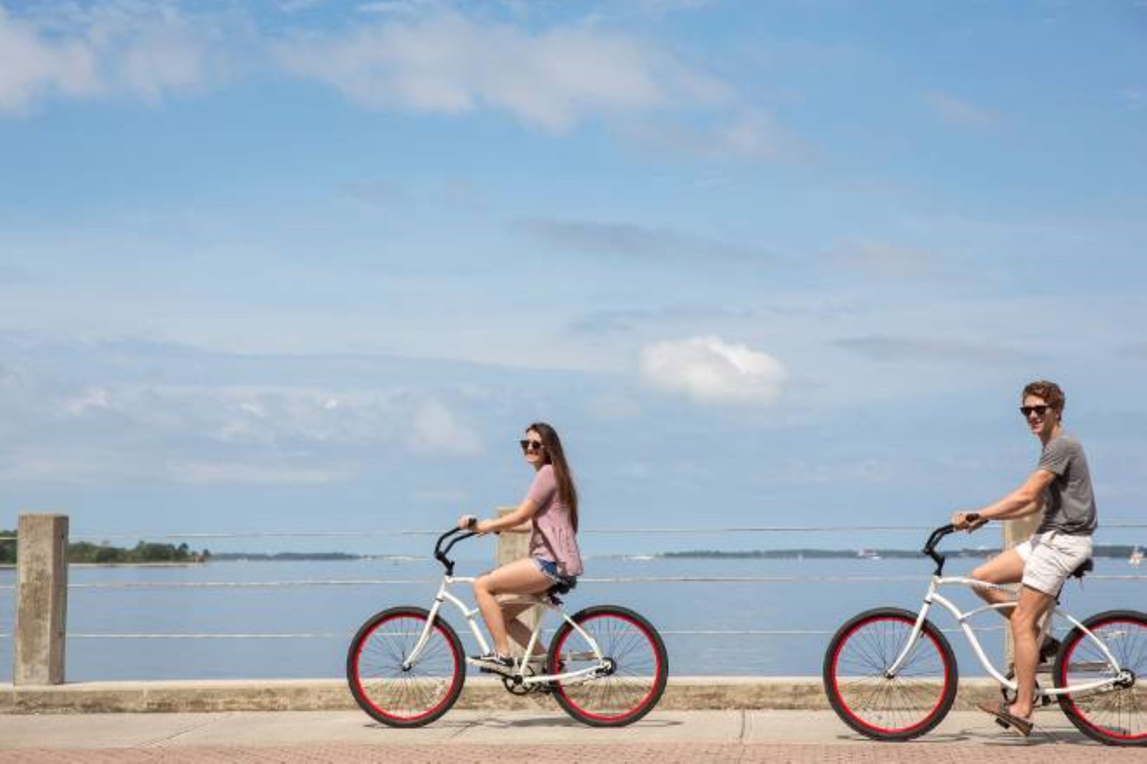 Twee personen fietsen langs een waterkant.